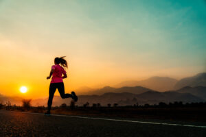 young woman enjoys running outside with beautiful summer evening countryside