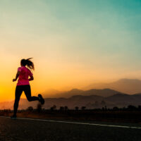 young woman enjoys running outside with beautiful summer evening countryside